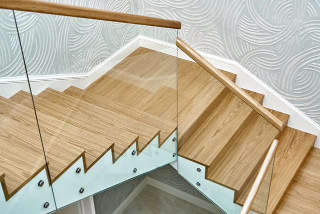 Chất liệu gỗ mang đến vẻ đẹp tự nhiên cho không gian. Việc kết hợp cầu thang kính với tay vịn gỗ là lựa chọn của nhiều gia chủ để tạo điểm nhấn cho căn phòng, hài hòa với các nội thất như là sofa, tủ gỗ, kệ gỗ trong nhà